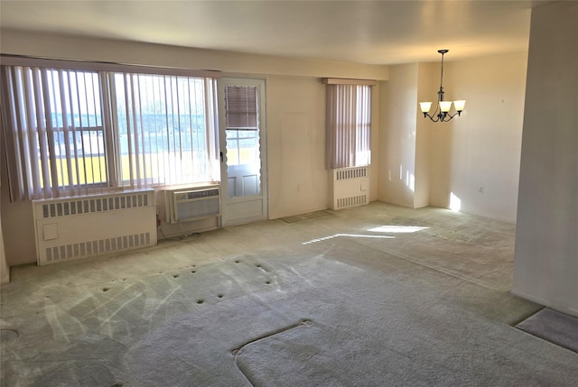 carpeted spare room featuring radiator, cooling unit, and a chandelier