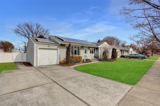 view of front of property with driveway, solar panels, an attached garage, fence, and a front yard