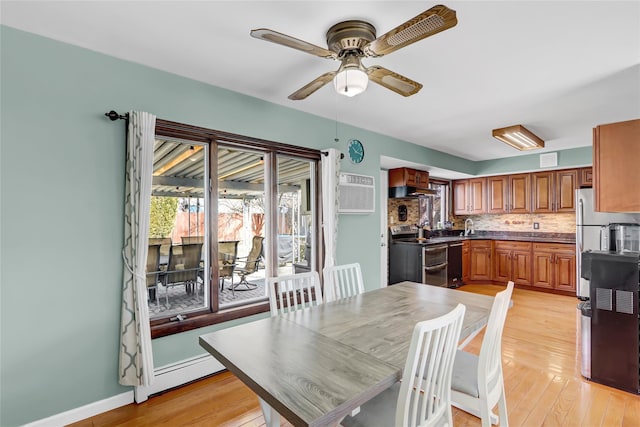 dining area featuring light wood-style flooring, baseboard heating, an AC wall unit, ceiling fan, and baseboards