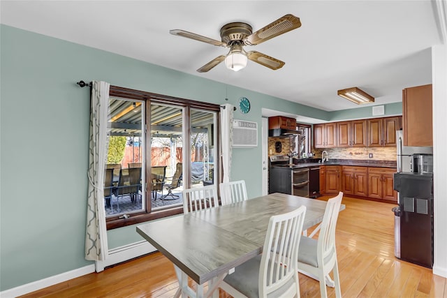 dining room featuring light wood-style floors, a ceiling fan, baseboards, and an AC wall unit