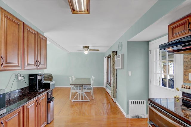 kitchen with range with two ovens, light wood-style flooring, under cabinet range hood, an AC wall unit, and radiator