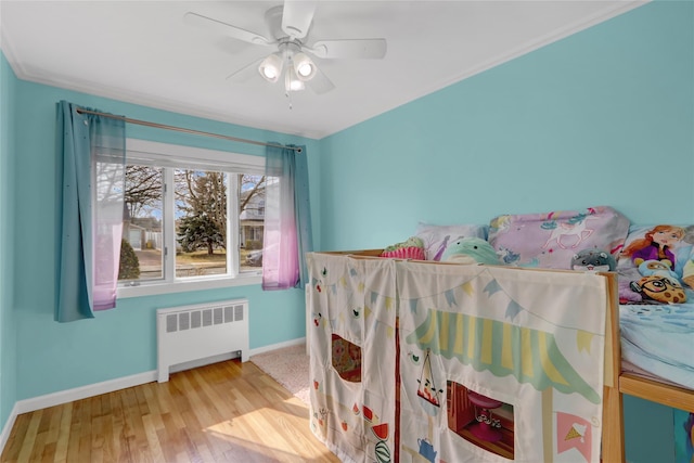 bedroom featuring radiator, ceiling fan, baseboards, and wood finished floors