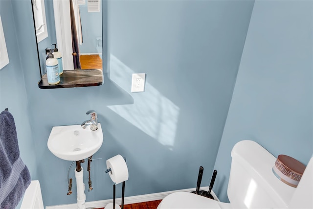 bathroom featuring toilet, baseboards, and a sink