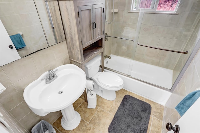 bathroom featuring tile walls, toilet, tile patterned flooring, combined bath / shower with glass door, and backsplash