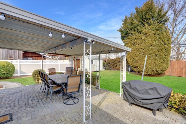 view of patio featuring a fenced backyard, a storage unit, outdoor dining area, and an outdoor structure