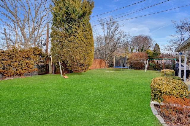 view of yard with a trampoline and fence