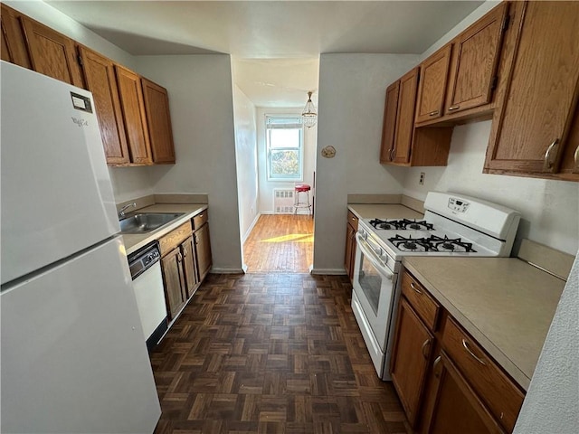 kitchen featuring brown cabinets, white appliances, light countertops, and a sink