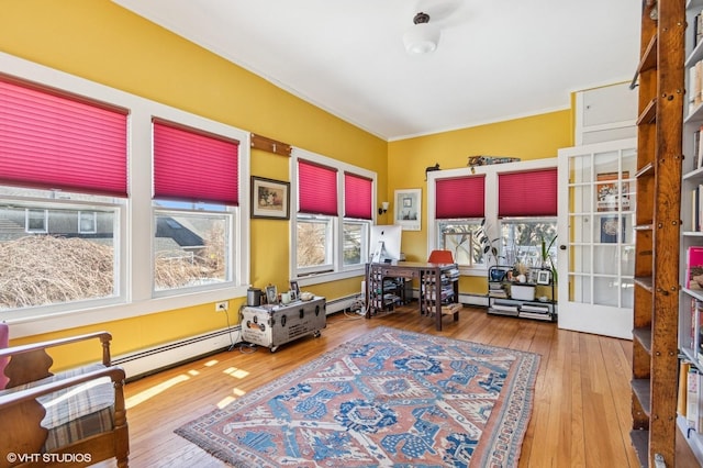 office space with a baseboard heating unit, wood finished floors, and crown molding