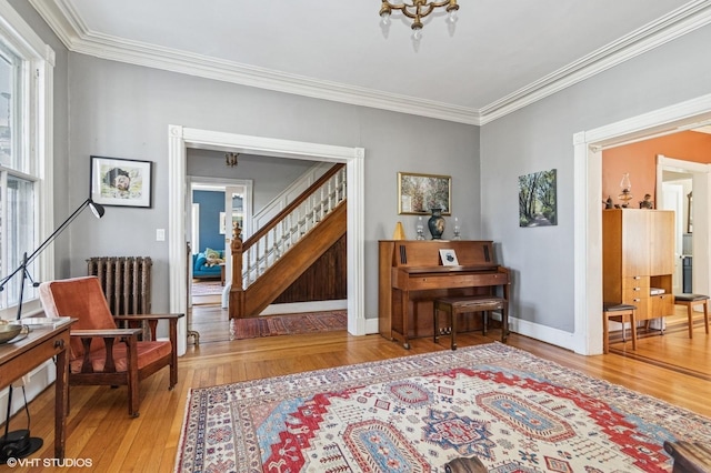 living area featuring radiator heating unit, stairs, ornamental molding, and wood finished floors