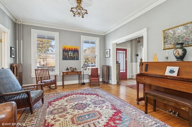 living area with crown molding, plenty of natural light, an inviting chandelier, and light wood-style floors