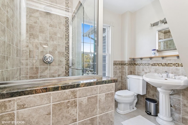 bathroom featuring a wainscoted wall, tile walls, toilet, and tile patterned floors