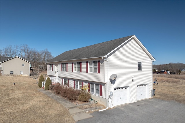 view of side of property featuring a garage and aphalt driveway