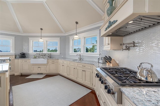 kitchen featuring stainless steel gas cooktop, custom range hood, a sink, and hanging light fixtures