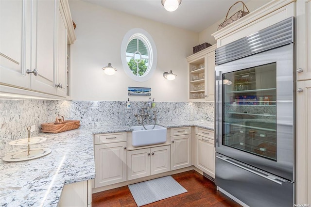 kitchen with beverage cooler, dark wood-style floors, light stone countertops, open shelves, and a sink