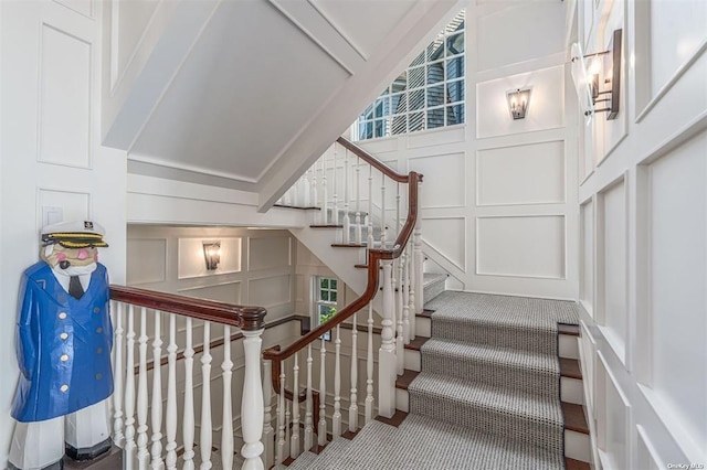 stairway with a decorative wall and carpet flooring