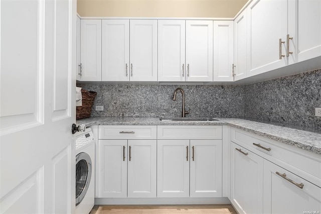 laundry area featuring cabinet space, a sink, and washer / dryer