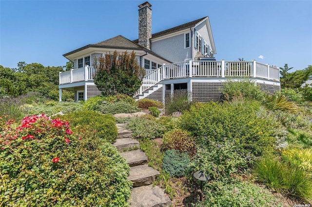 back of property featuring a chimney, a deck, and stairs