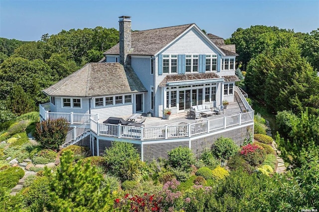 back of house with stairs, a chimney, a deck, and an outdoor hangout area