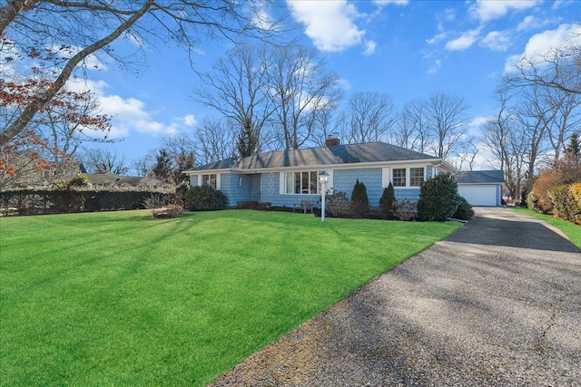 view of front facade with an outbuilding, a detached garage, a chimney, and a front yard