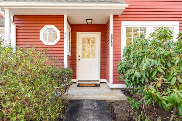 view of exterior entry featuring a shingled roof