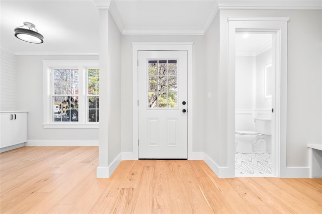 entrance foyer with light wood-type flooring, a healthy amount of sunlight, and ornamental molding