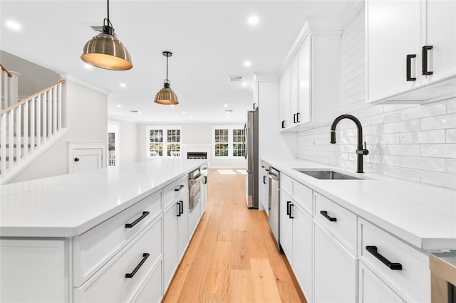 kitchen featuring light wood-style flooring, a sink, tasteful backsplash, a center island, and appliances with stainless steel finishes