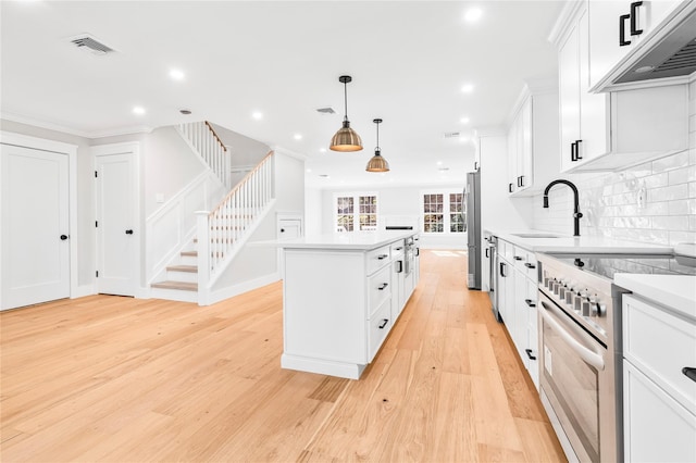 kitchen featuring under cabinet range hood, stainless steel appliances, a kitchen island, and light countertops