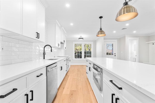 kitchen featuring a sink, decorative backsplash, ornamental molding, light countertops, and stainless steel appliances