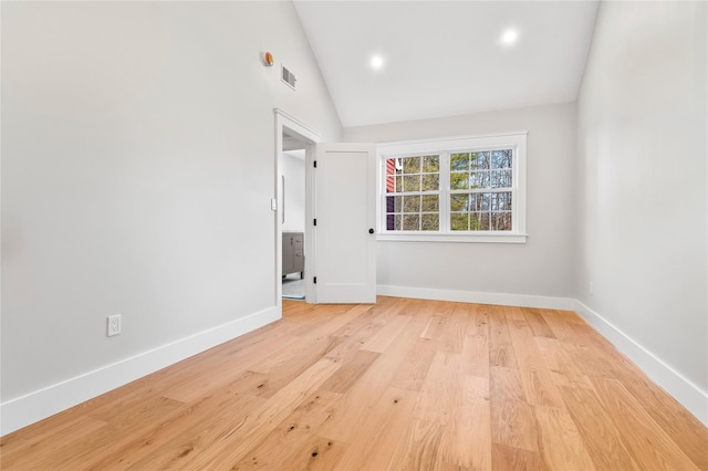 unfurnished room featuring light wood-type flooring, visible vents, baseboards, and vaulted ceiling