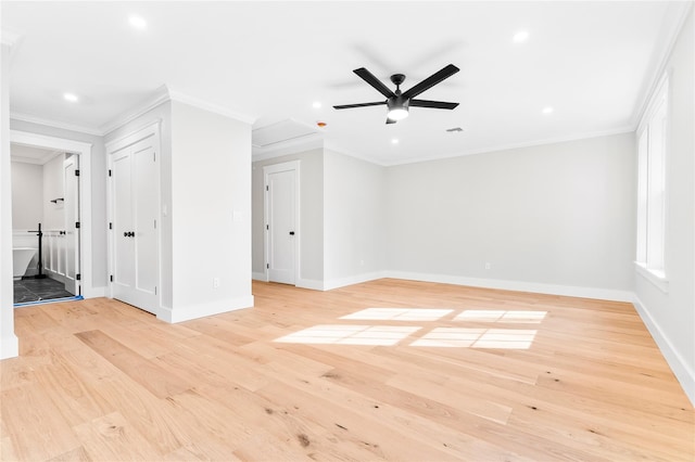 empty room with a ceiling fan, crown molding, light wood-style floors, and baseboards