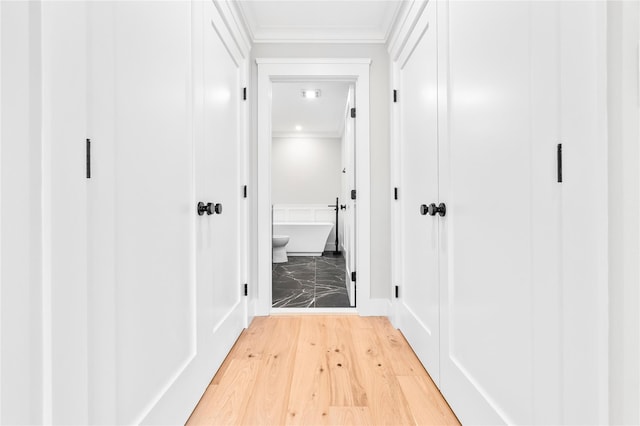 corridor with light wood-style flooring and ornamental molding