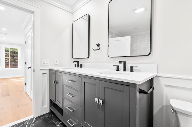 bathroom with a sink, toilet, marble finish floor, and ornamental molding