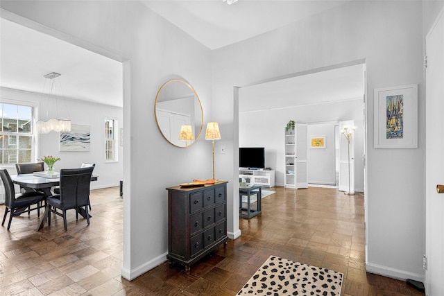 hall featuring a chandelier and baseboards