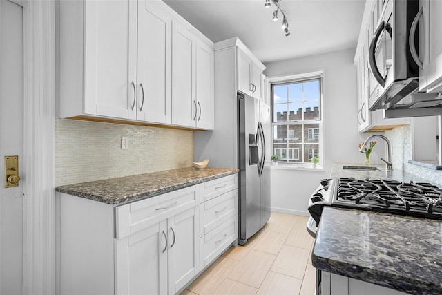 kitchen featuring stainless steel appliances, white cabinets, a sink, and tasteful backsplash