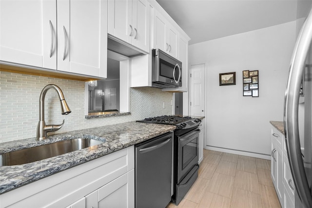 kitchen featuring stainless steel appliances, stone countertops, white cabinetry, and a sink