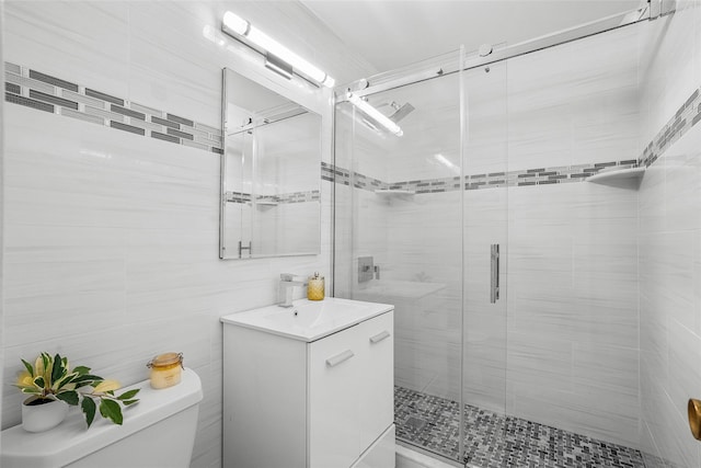 bathroom featuring a stall shower, vanity, toilet, and tile walls