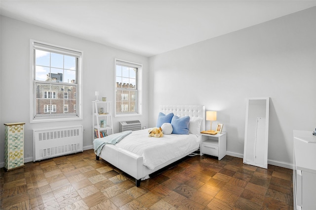 bedroom with baseboards, a wall unit AC, and radiator heating unit