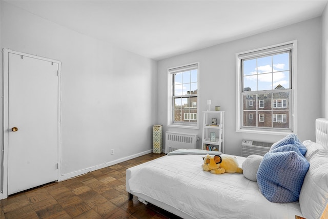 bedroom featuring radiator, baseboards, and a wall mounted AC