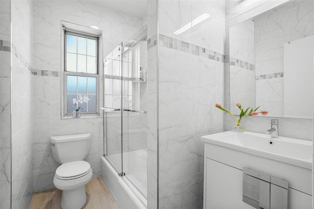 bathroom with wood finished floors, tile walls, toilet, and vanity