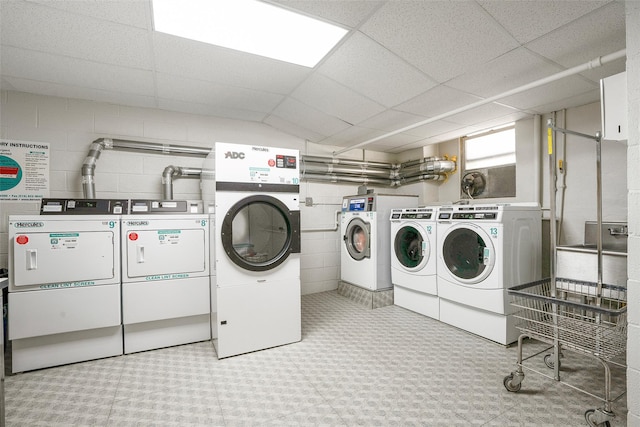 community laundry room featuring washing machine and dryer and concrete block wall