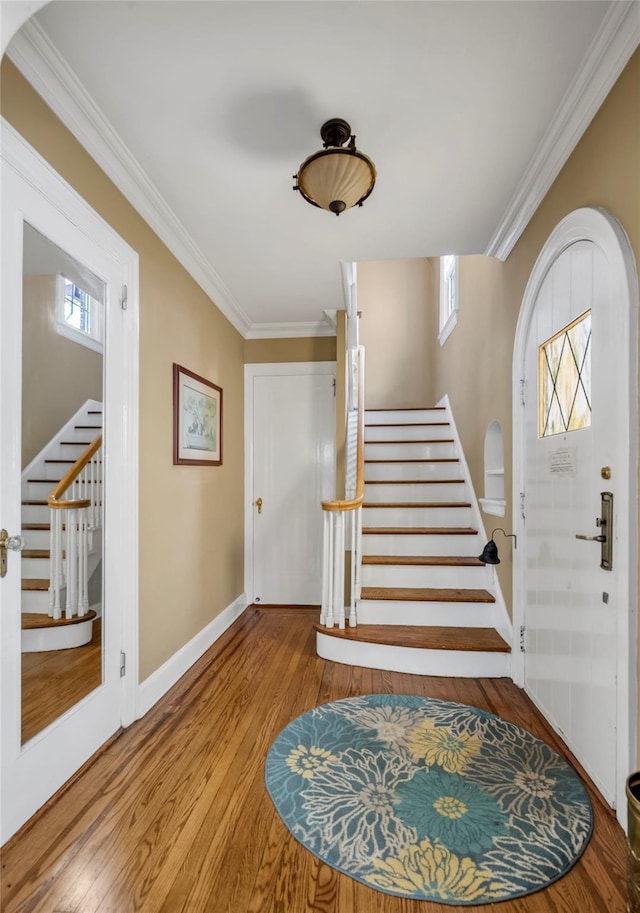 entrance foyer with ornamental molding, a wealth of natural light, stairway, and wood finished floors