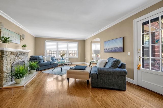 living area with a stone fireplace, plenty of natural light, and light wood-style floors