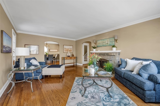 living room featuring baseboards, a fireplace, arched walkways, and wood finished floors