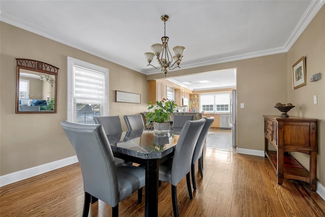 dining room featuring ornamental molding, light wood-type flooring, and baseboards