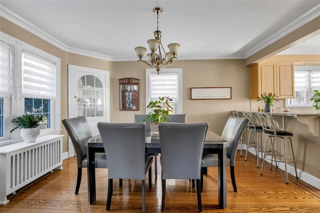 dining room featuring radiator, crown molding, an inviting chandelier, and wood finished floors