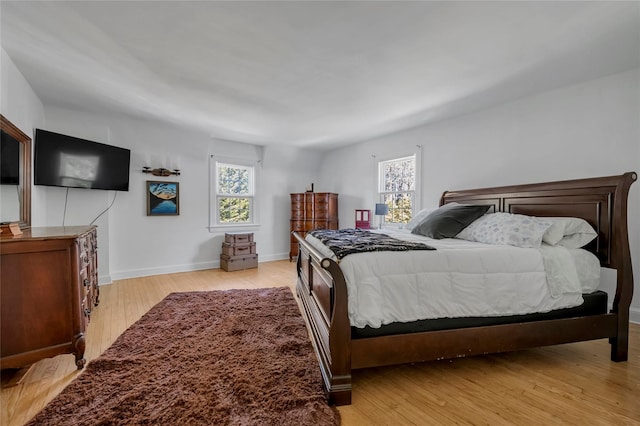 bedroom with light wood-style flooring, multiple windows, and baseboards