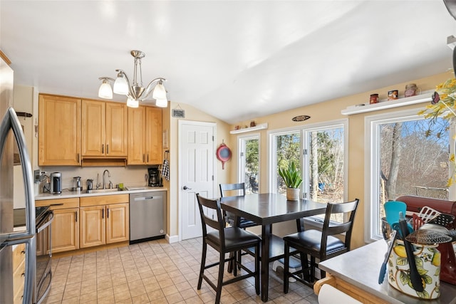 kitchen featuring stainless steel appliances, lofted ceiling, light countertops, an inviting chandelier, and a sink