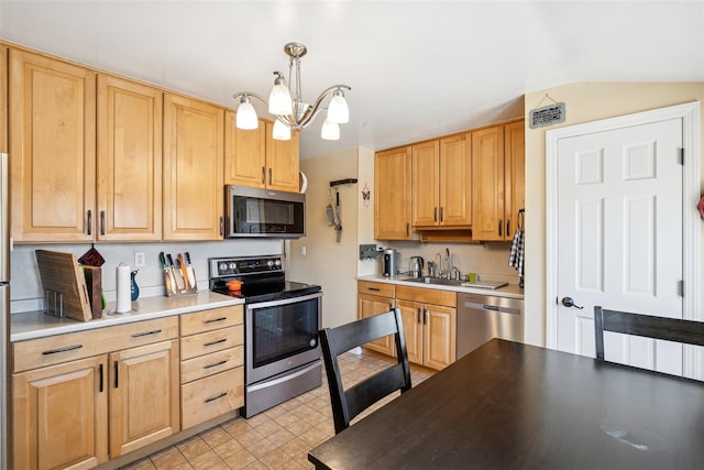 kitchen with appliances with stainless steel finishes, light brown cabinets, a sink, and an inviting chandelier