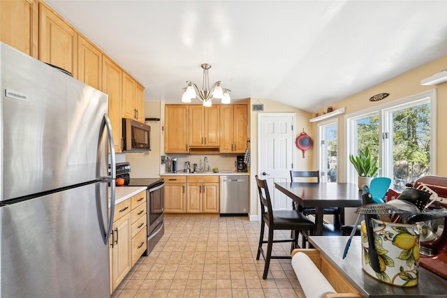 kitchen with appliances with stainless steel finishes, hanging light fixtures, light countertops, a chandelier, and a sink