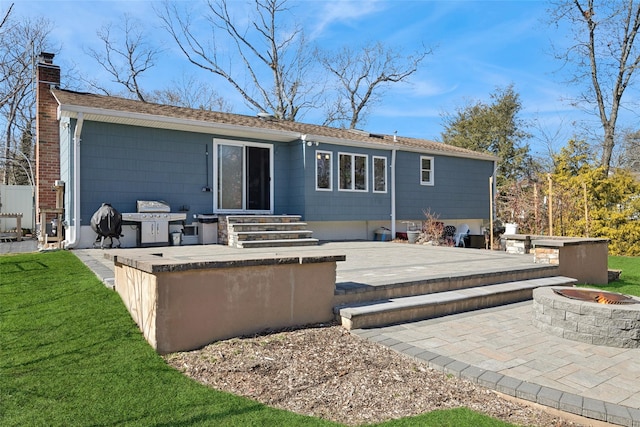 back of property featuring a fire pit, a patio, exterior kitchen, and a chimney